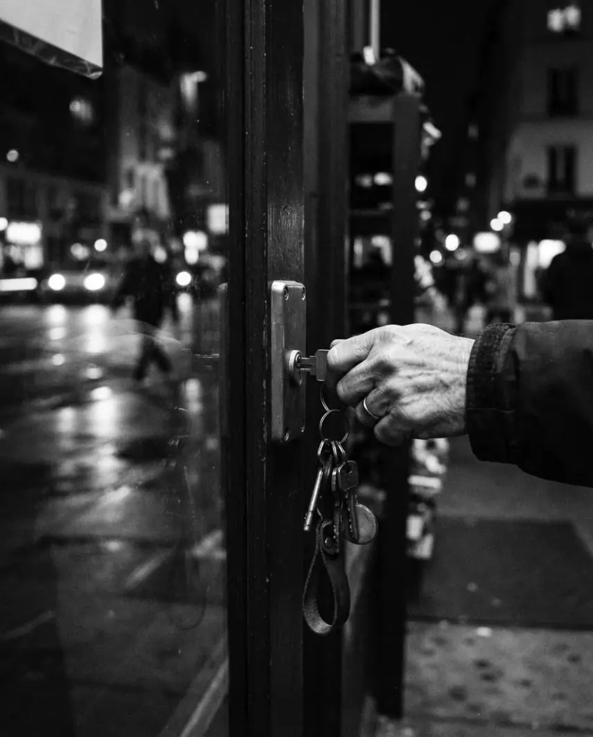 Main qui verrouille la porte vitrée d'un commerce